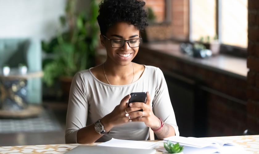 Young woman smiling while holding her phone.