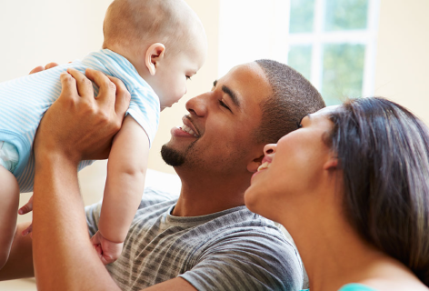 Father holding high his baby while mother watch them