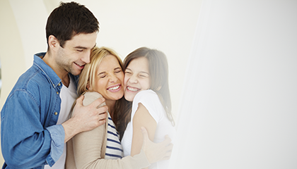 Mother and father hugging their teenage daughter.