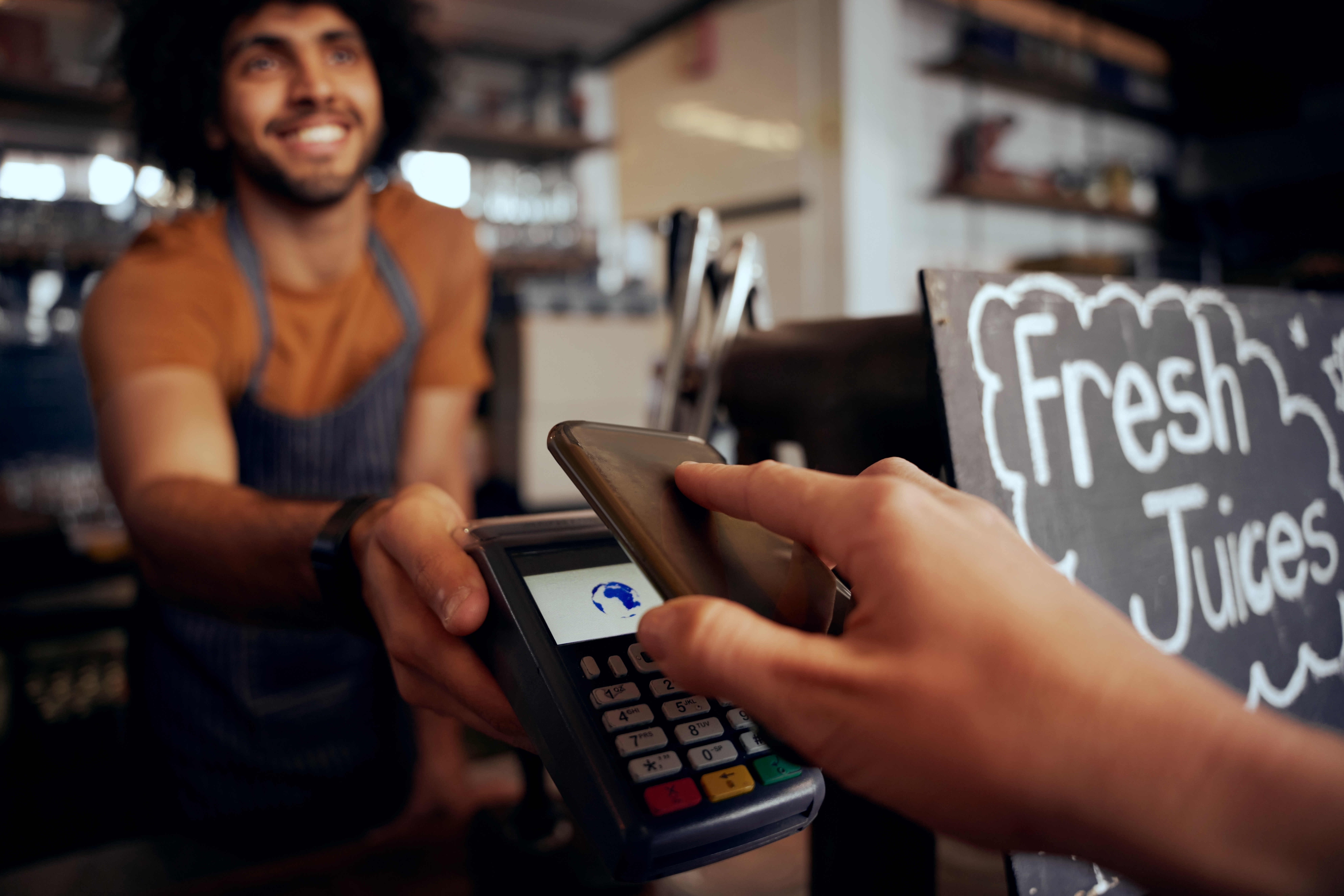 Closeup of hand making contactless payment in cafe using smartphone