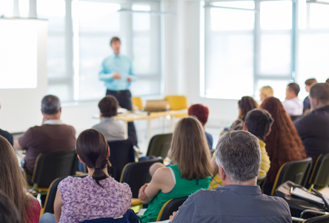 Bunch of people listening at a person in a seminar