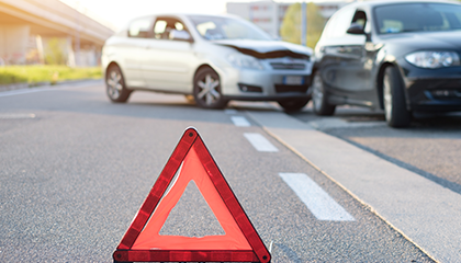 Triángulo rojo de emergencia frente a un accidente automovilístico.