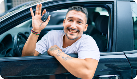 Man riding in his new car, smiling and showing the car keys.