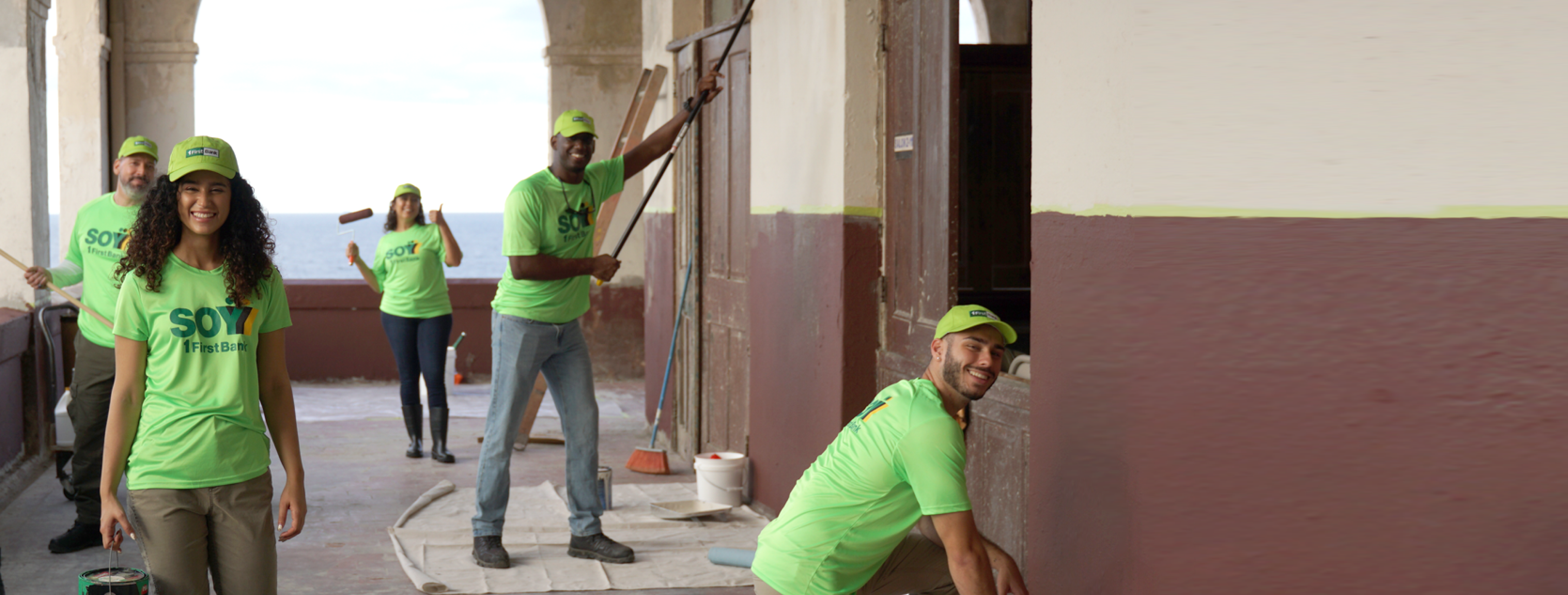 People in green painting a wall