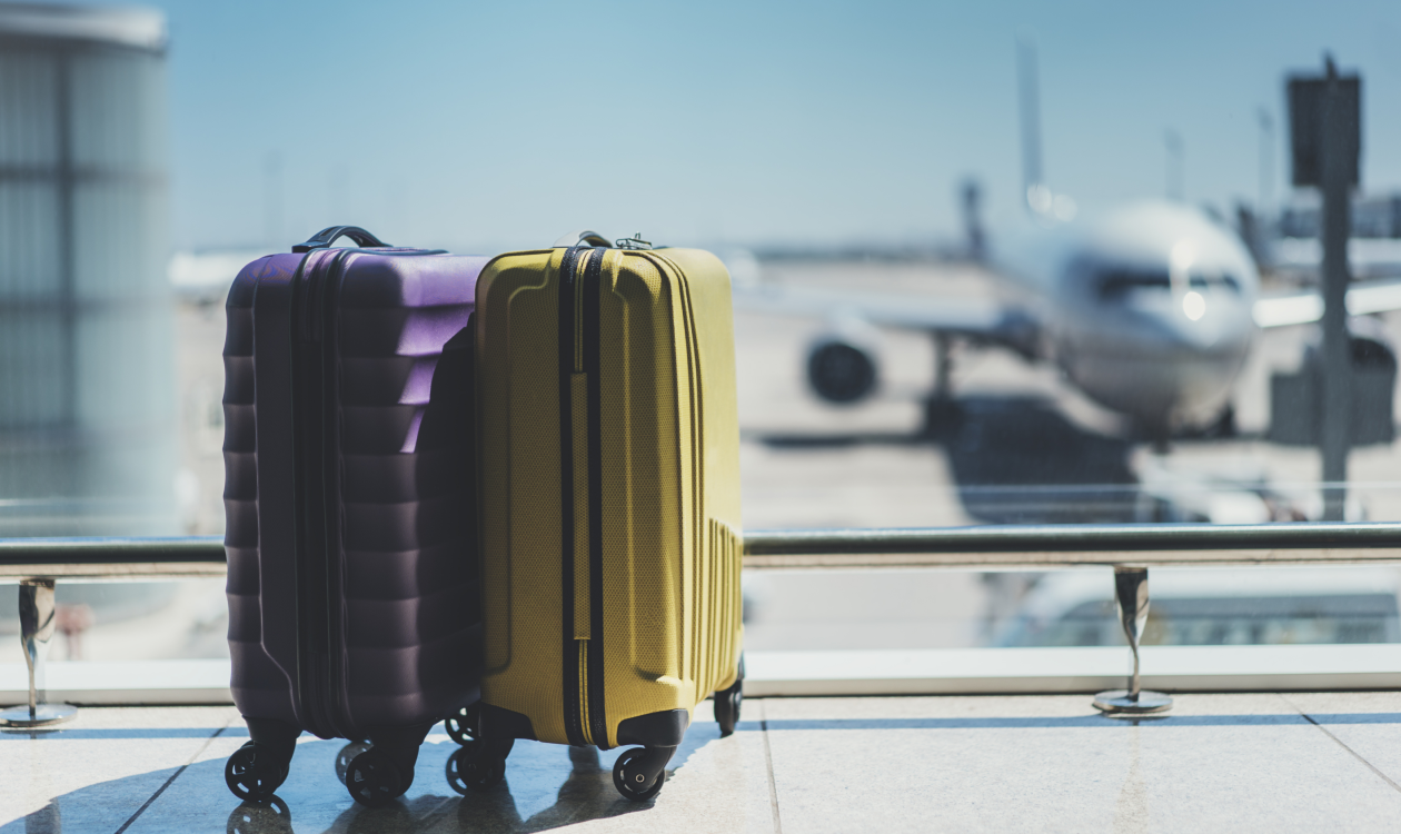 Travel suitcases in front of airplane.