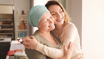 Woman holding a cancer patient wearing a light blue chemo turban