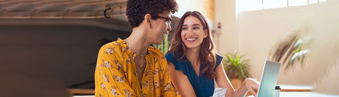 girl points something on a laptop to lady