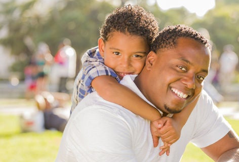 Father smiling while kid holds at his neck