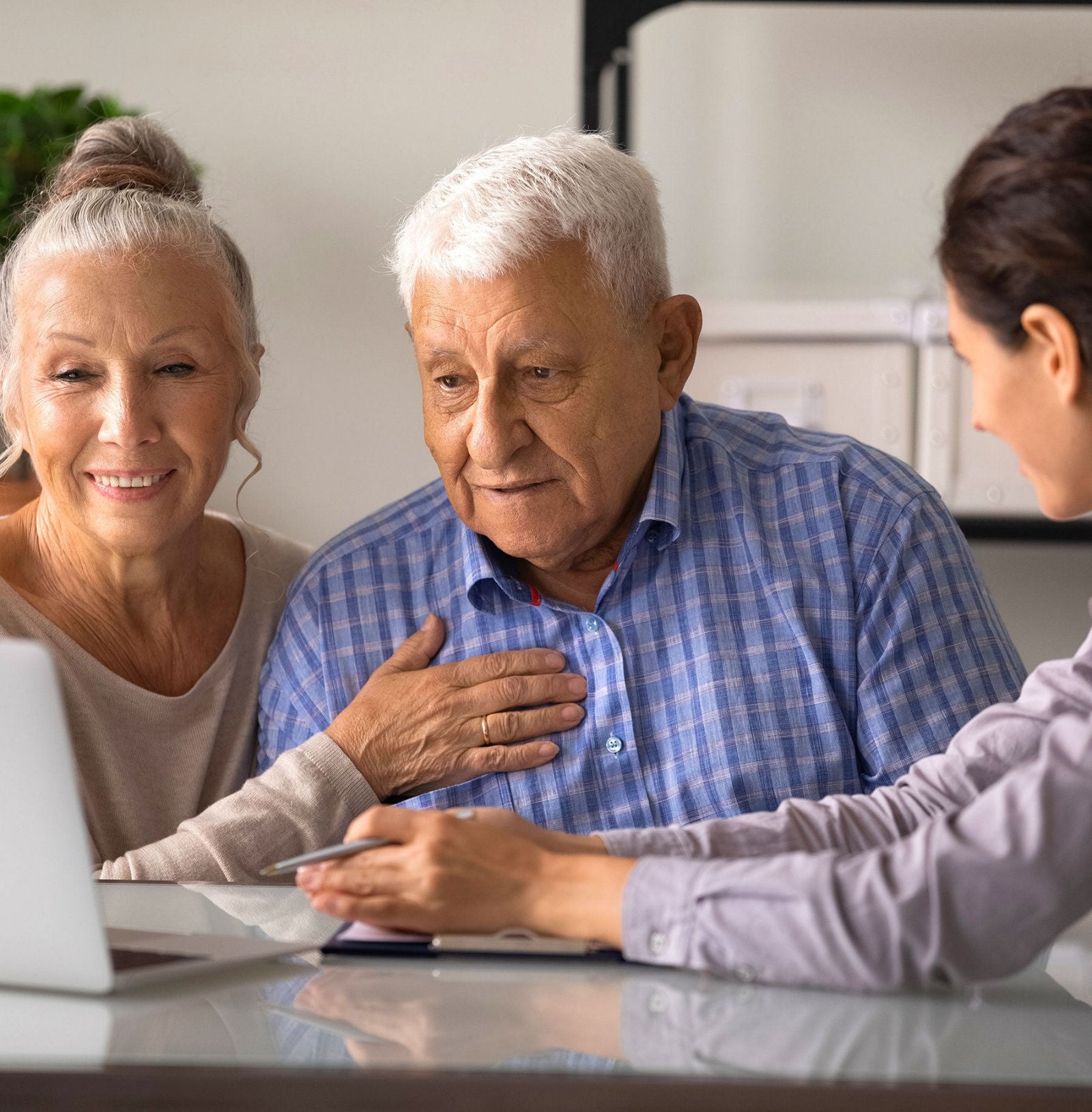 Senior couple smiling and looking at a laptop.