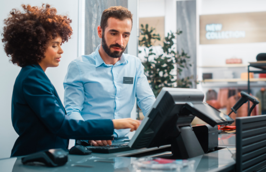 Two cashiers looking at a computer