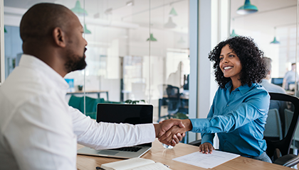 Woman shaking hands with a man over a desk