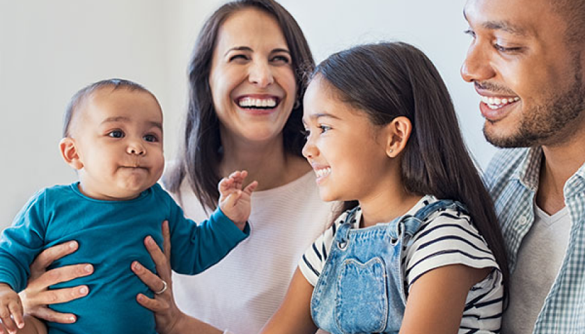 smiling family of four with two baby kids