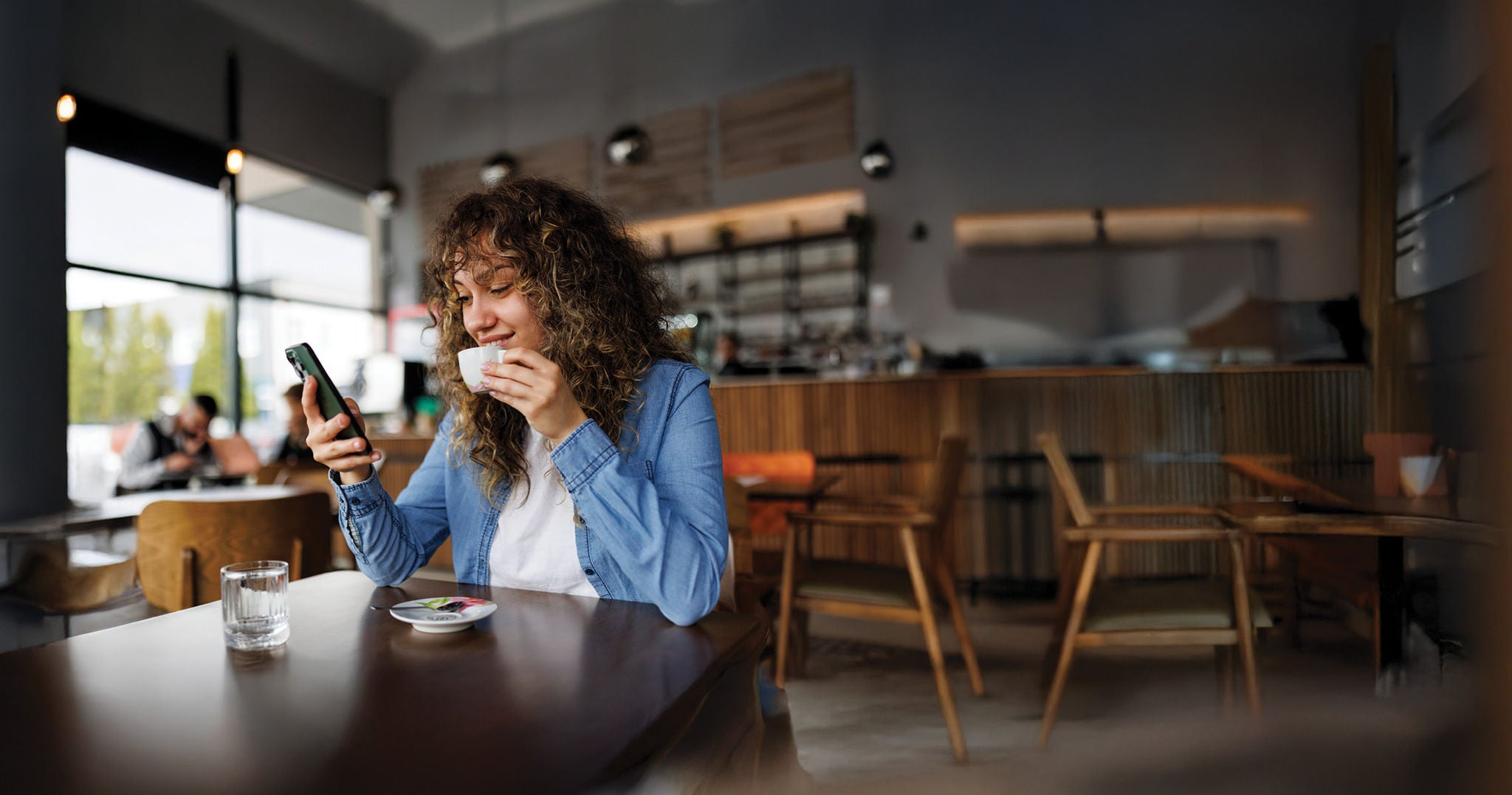 Woman drinking a coffe with a mobile device in hand