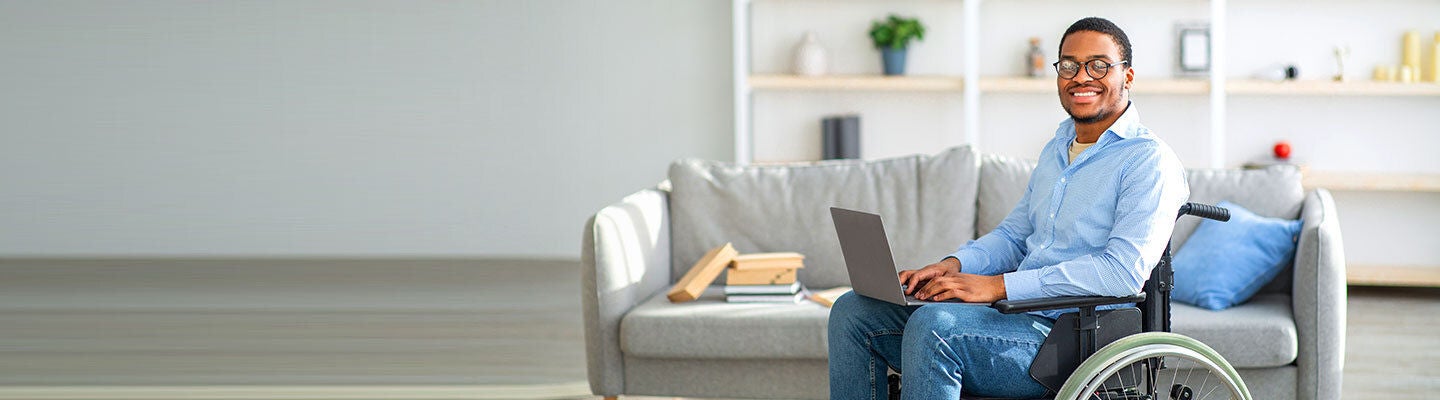 Smiling man in wheelchair typing a computer