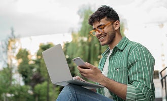 Young man using cellphone and computer