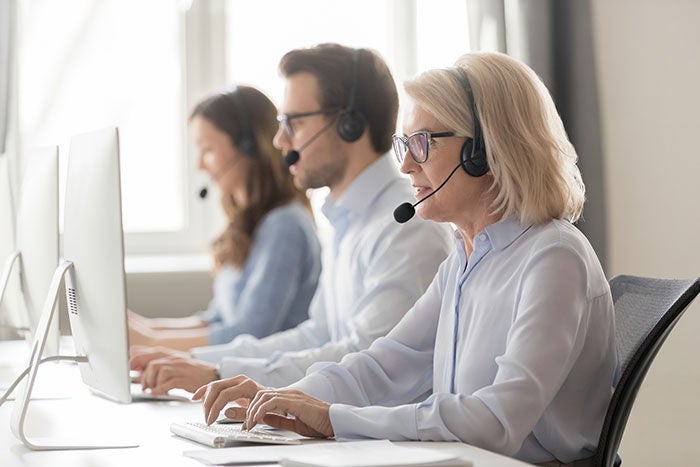 Three people with headphones in front of computers