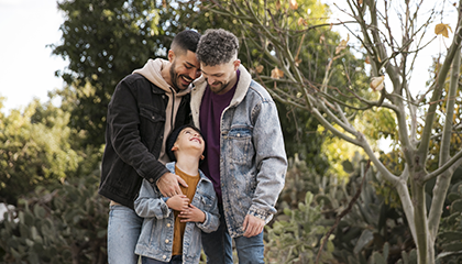 Pareja se miran sonriendo mientras abrazan a su hijo 