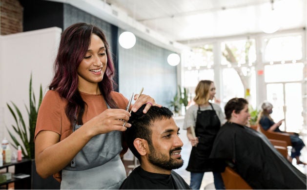 Woman hairdresser cutting hair to man