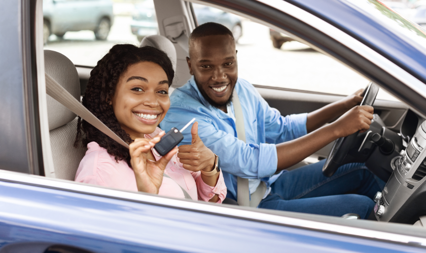Man driving his car while smiling with his partner as co-driver.