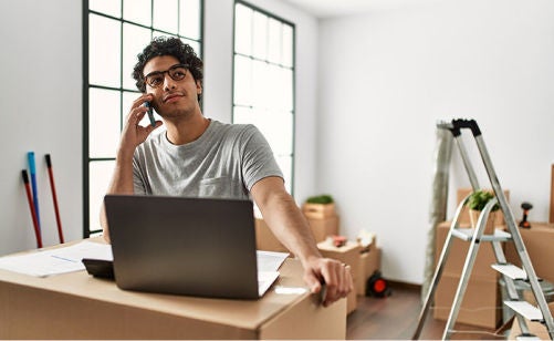 young man makes a call in front of his laptop