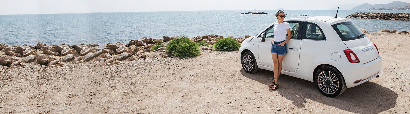 woman leaning on her car near the sea