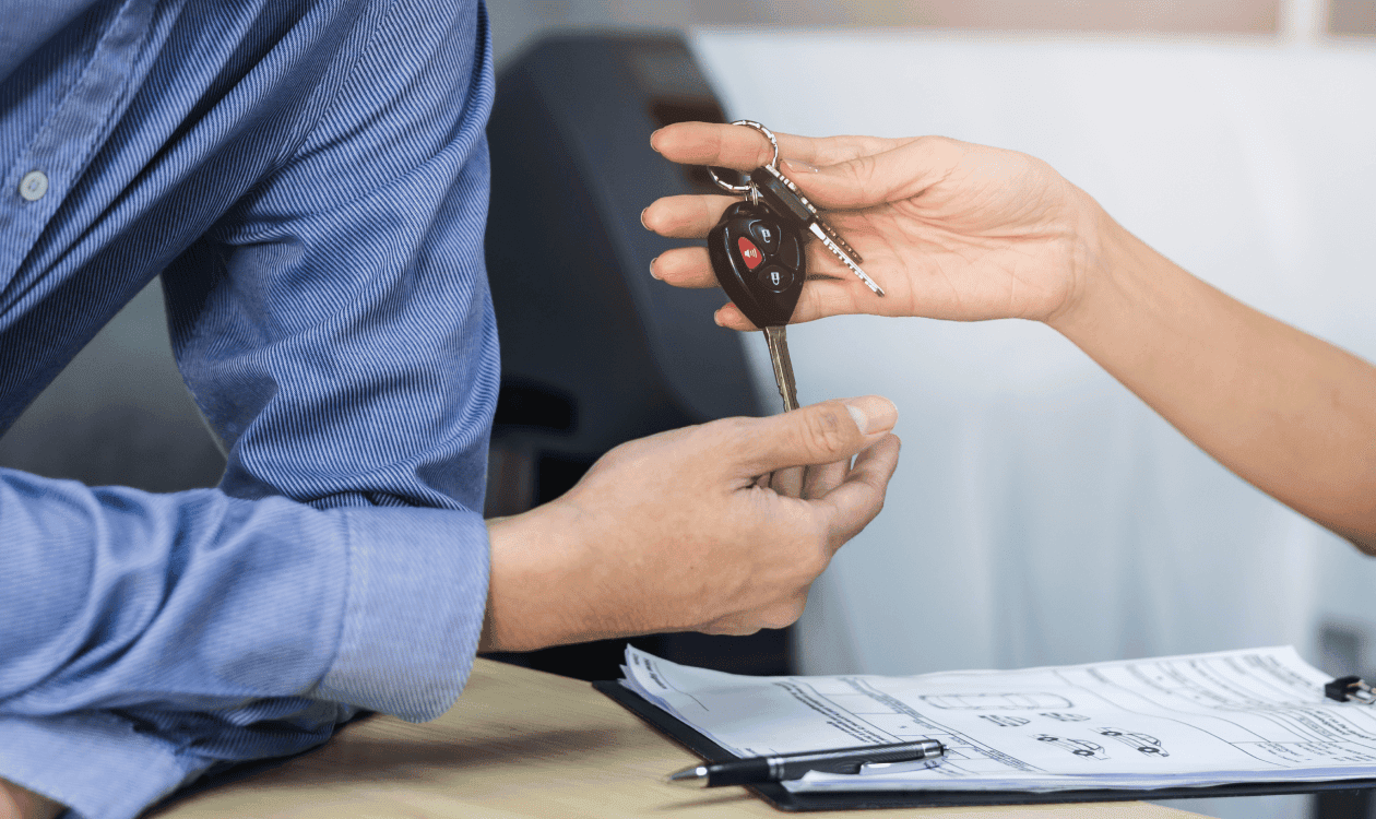 Hombre recibiendo llaves de auto con papeles firmados.