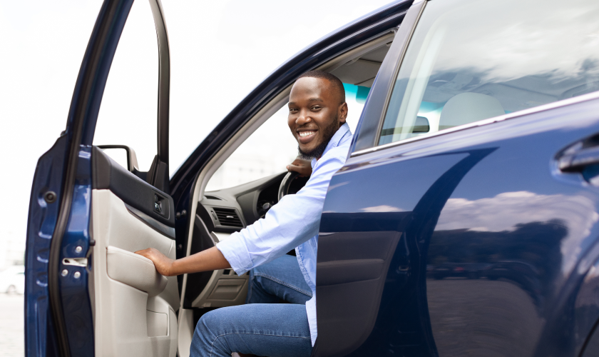 Man smiling in a blue car.