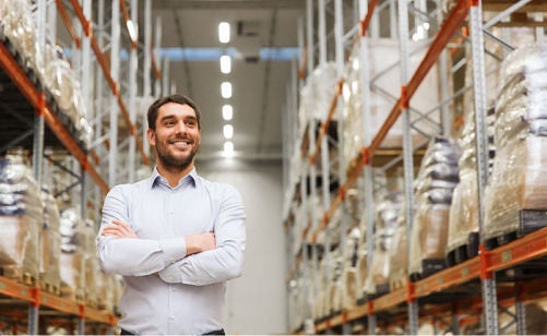 gentleman with crossed arms smiles in a warehouse