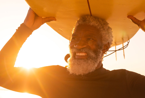 Old man with neoprene suit holding a surfboard