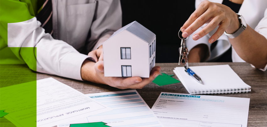 person holding a tiny paper house besides another holding house keys