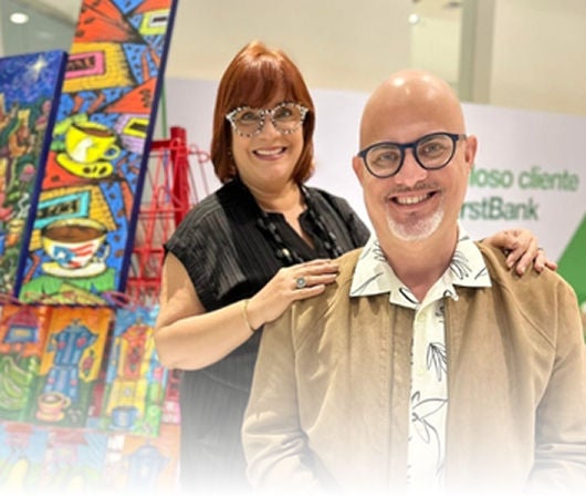 Dueños posando frente a pinturas coloridas de Boceteo Arte Alegre.