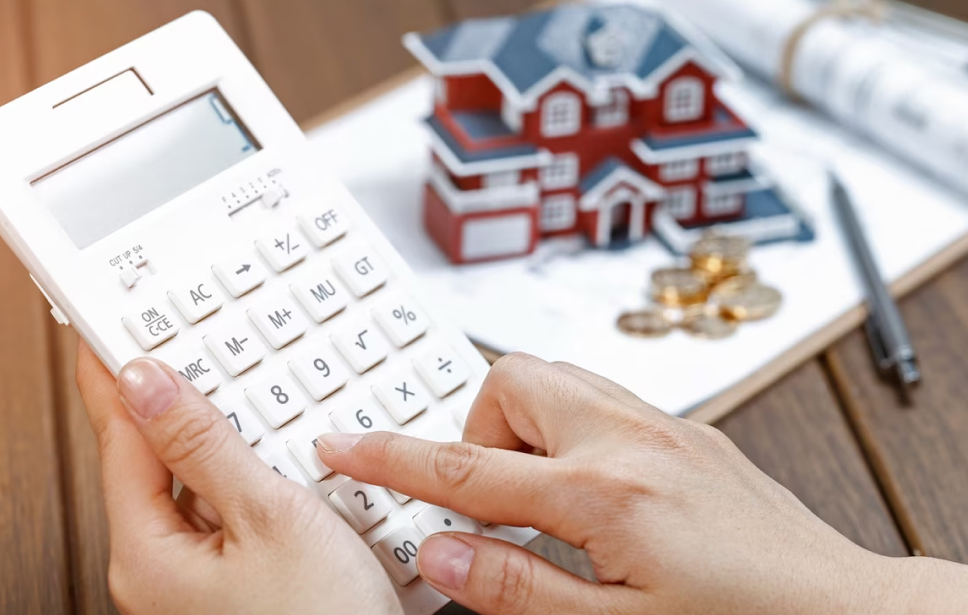 hand with a calculator and a small house