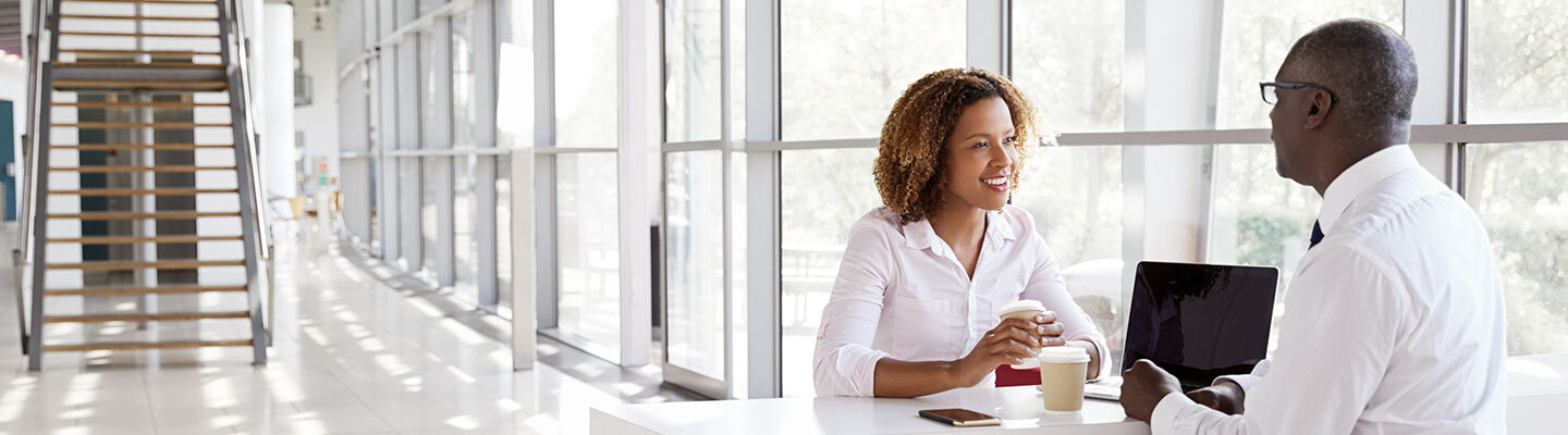 two people sitting in an office talking and smiling