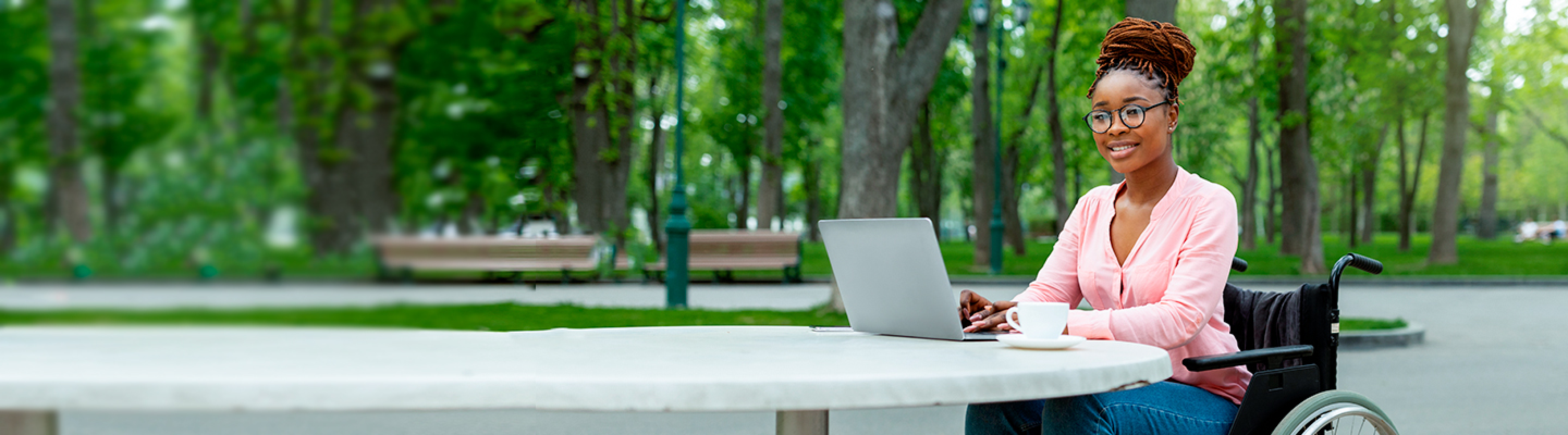 Woman in a wheelchair with her laptop and a cup of coffee