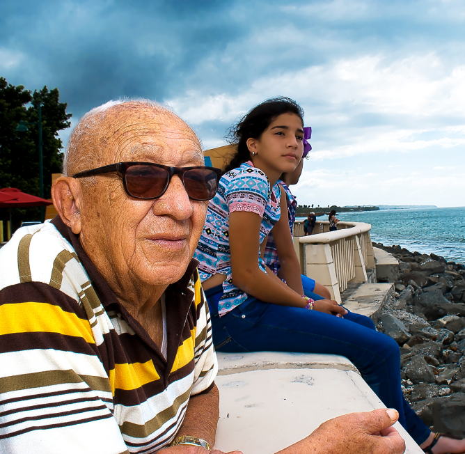 Senior man and girl looking out to sea.