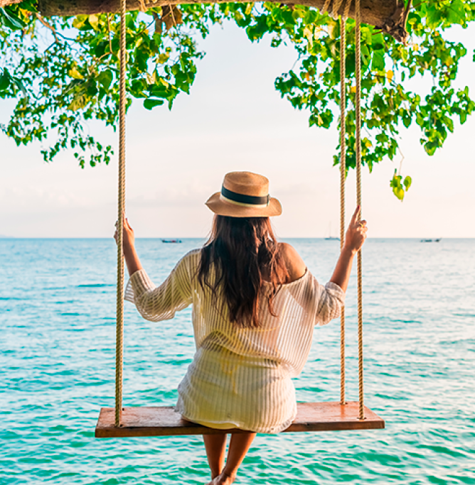 Woman on swing looking out to sea.