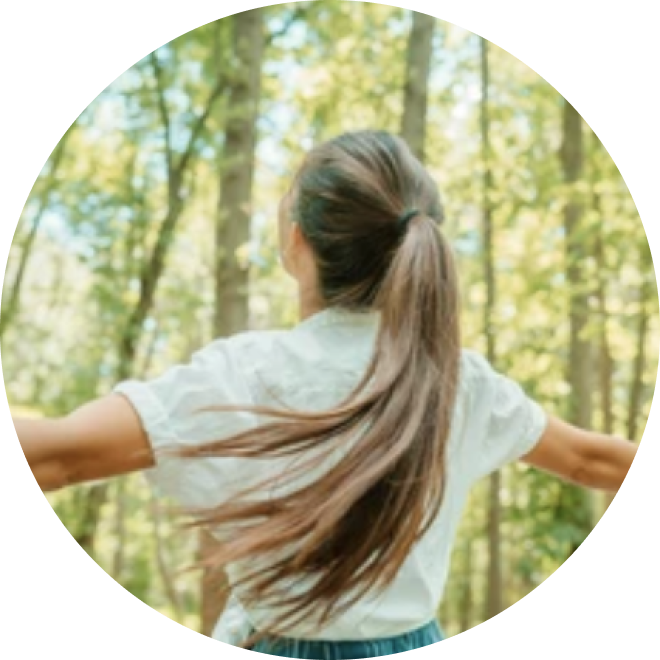 Woman opens her arms to the forest.