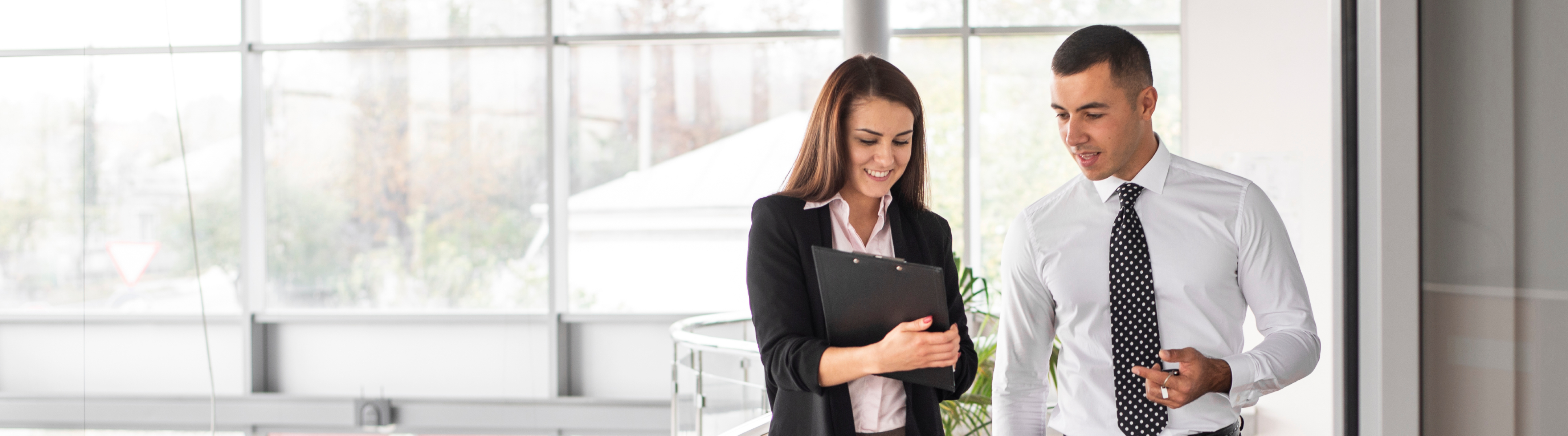 Woman in black jacket with folder in hand and man in white shirt