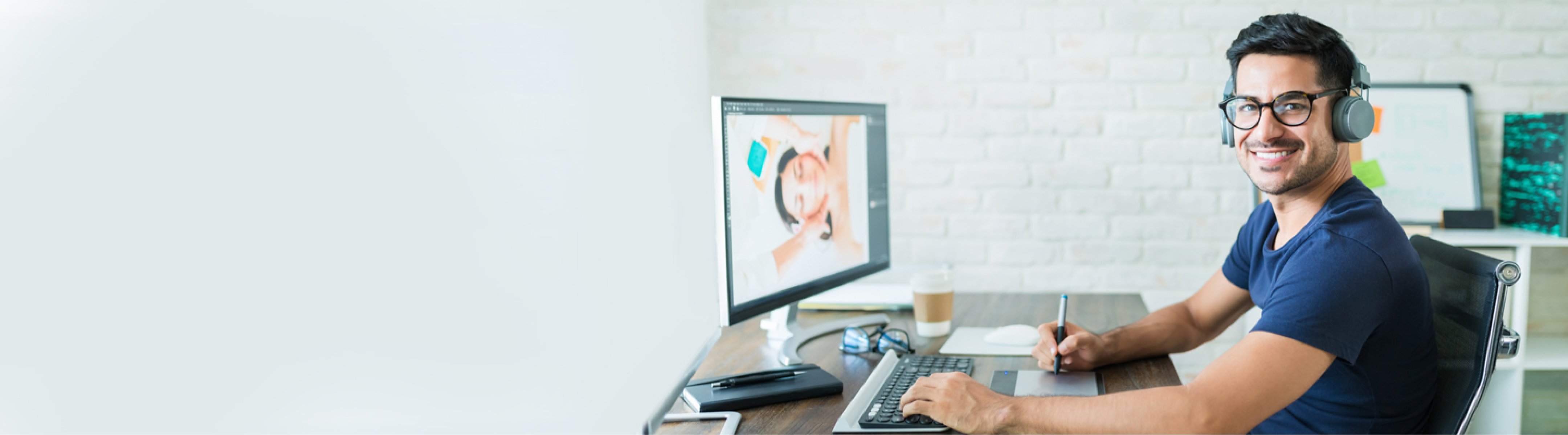 Man with glasses smiling while working on his computer.