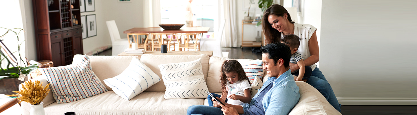 Family sitting on the sofa looking at a tablet