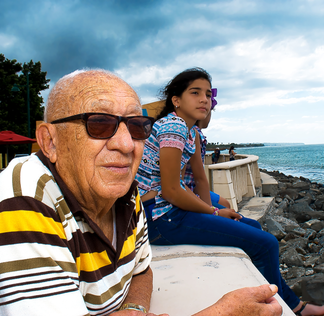 Hombre mayor y niña mirando hacia el mar.