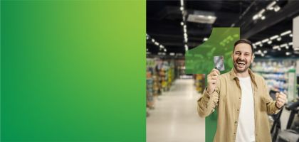 Joven  feliz en supermercado con tarjeta beyond en mano